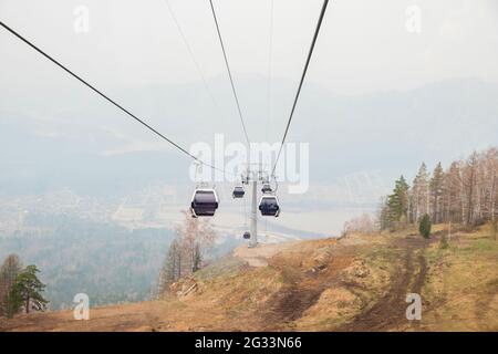 Cabine di ascensore in una stazione sciistica di montagna. Pista di risalita sulla stazione invernale di montagna hilghland in giornata nuvolosa. Funivia per la seggiovia con le persone. Scenico Foto Stock