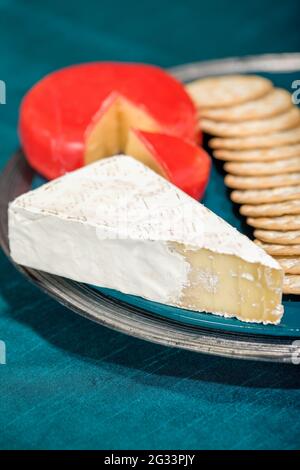 Baby Brie affumicato e formaggio Gouda, insieme con cracker d'acqua sul piatto Foto Stock