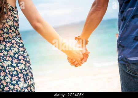 Coppia amante tenere le mani insieme sulla spiaggia tropicale estiva. Concentrarsi sulle mani con l'attività di felicità. Amore romantico viaggio insieme. Vacanze estive Foto Stock