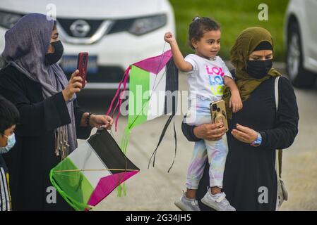 San Salvador, El Salvador. 13 giugno 2021. Una donna che indossa un hijab tiene un bambino che gioca con un aquilone che mostra i colori della bandiera palestinese durante la dimostrazione. I membri della comunità palestinese di El Salvador manifestano contro gli attacchi sferrati da Israele contro la Palestina, che ha causato centinaia di morti e migliaia di sfollati. (Foto di Camilo Freedman/SOPA Images/Sipa USA) Credit: Sipa USA/Alamy Live News Foto Stock