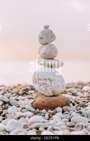 Pietre equilibrate sulla spiaggia all'alba Foto Stock