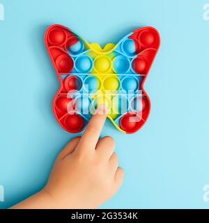 Giocattolo antistress alla moda. Bambino anonimo con gioco di poppit colorato. Immagine del giocattolo trendy Pop it fidget . Vista dall'alto del nuovo giocattolo sensoriale Foto Stock