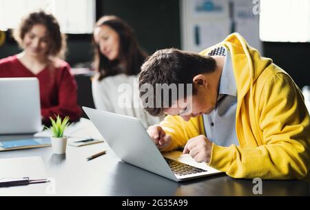 Uomo con sindrome da Down con computer portatile che frequenta la classe di istruzione nel centro della comunità, inclusività di persone disabili. Foto Stock