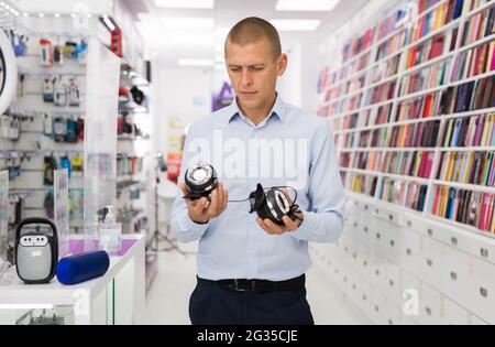 Acquirente maschile sceglie altoparlanti nel negozio di elettronica di consumo Foto Stock