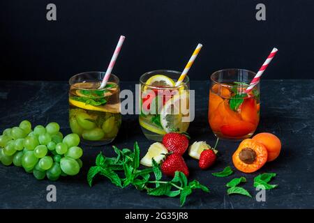 Estate bevande sane, limonata in bicchieri con paglia su sfondo nero. Foto Stock