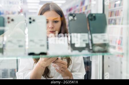 Donna che guarda gli smartphone al negozio multimediale Foto Stock