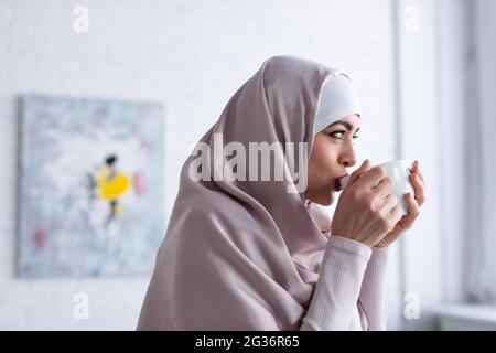 bella donna musulmana in hijab bere tè a casa Foto Stock