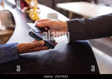 Sezione centrale dell'uomo che effettua un pagamento con carta di credito ad un caffè Foto Stock