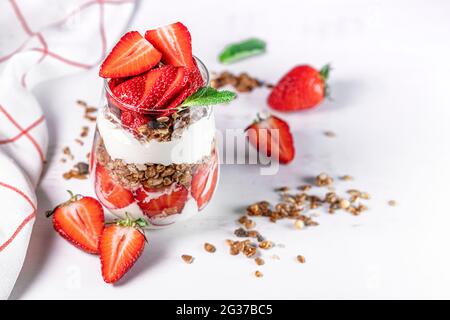 Colazione salutare con fragole preparate con fragole fresche, yogurt e muesli in bicchieri. Foto Stock
