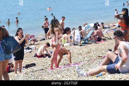 Brighton UK 14 giugno 2021 - tempo di posa per alcune fotografie come la folla godere del sole caldo sulla spiaggia di Brighton oggi come le temperature sono previste per raggiungere l'alto centigradi 20 nel Sud-est ancora : Credit Simon Dack / Alamy Live News Foto Stock