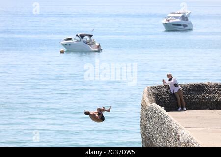 Brighton, Regno Unito. 14 Giugno 2021. Un cercatore di brivido fa un rovesciamento indietro sopra il muro dell'inguine e nel mare mentre la temperatura aumenta sulla costa meridionale. Credit: James Boardman/Alamy Live News Foto Stock