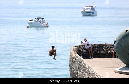 Brighton, Regno Unito. 14 Giugno 2021. Un cercatore di brivido fa un rovesciamento indietro sopra il muro dell'inguine e nel mare mentre la temperatura aumenta sulla costa meridionale. Credit: James Boardman/Alamy Live News Foto Stock