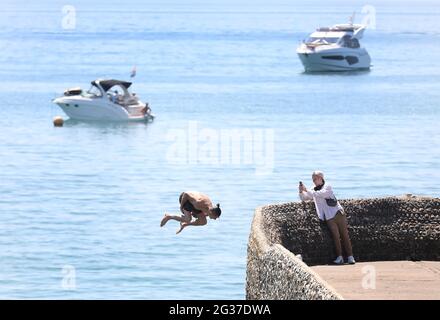 Brighton, Regno Unito. 14 Giugno 2021. Un cercatore di brivido fa un rovesciamento indietro sopra il muro dell'inguine e nel mare mentre la temperatura aumenta sulla costa meridionale. Credit: James Boardman/Alamy Live News Foto Stock