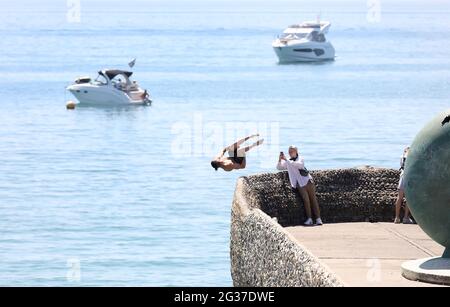 Brighton, Regno Unito. 14 Giugno 2021. Un cercatore di brivido fa un rovesciamento indietro sopra il muro dell'inguine e nel mare mentre la temperatura aumenta sulla costa meridionale. Credit: James Boardman/Alamy Live News Foto Stock