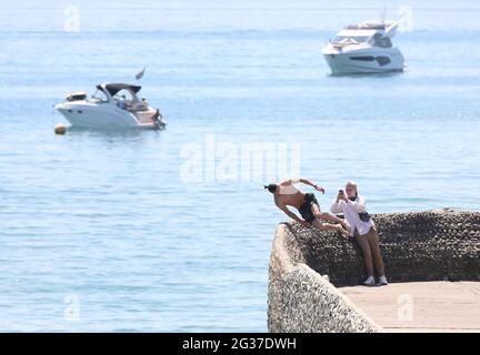 Brighton, Regno Unito. 14 Giugno 2021. Un cercatore di brivido fa un rovesciamento indietro sopra il muro dell'inguine e nel mare mentre la temperatura aumenta sulla costa meridionale. Credit: James Boardman/Alamy Live News Foto Stock