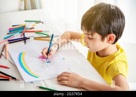 bambino disegna la sua famiglia su un pezzo di carta con matite colorate. Concetto di psicologia infantile. Foto Stock