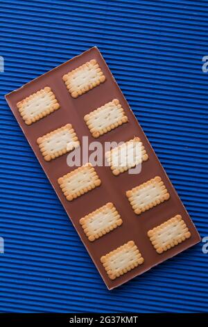 Bar al cioccolato con biscotti croccanti su sfondo blu. Foto Stock