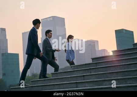 team di tre dirigenti aziendali asiatici che camminano nel quartiere finanziario del centro Foto Stock