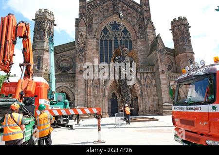 Hereford, Herefordshire, Regno Unito - Lunedi 14 giugno 2021 - i appaltatori iniziano il processo di sollevamento e installazione della statua dell'angelo del coltello fuori della cattedrale - la statua alta 3.5 metri è composta da 100,000 coltelli confiscati ed è stata creata dallo scultore Alfie Bradley. La statua dell'Angelo dei coltelli aumenta la consapevolezza dell'impatto del crimine dei coltelli e sarà esposta all'esterno della cattedrale di Hereford fino al 12 luglio 2021. Photo Steven May / Alamy Live News Foto Stock