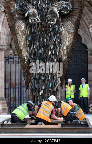 Hereford, Herefordshire, Regno Unito - Lunedi 14 giugno 2021 - i contraenti lavorano per assicurare la statua dell'angelo del coltello fuori della cattedrale - la statua alta 3.5 metri è fatta di 100,000 coltelli confiscati ed è stata creata dallo scultore Alfie Bradley. La statua dell'Angelo dei coltelli aumenta la consapevolezza dell'impatto del crimine dei coltelli e sarà esposta all'esterno della cattedrale di Hereford fino al 12 luglio 2021. Photo Steven May / Alamy Live News Foto Stock