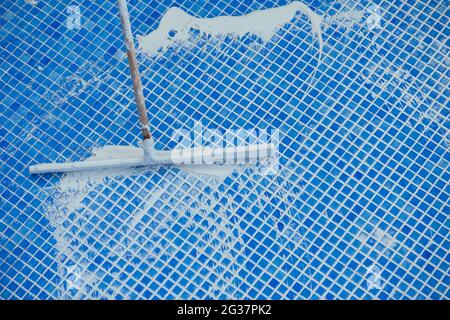 Lavoratore che copre le fiamme sulla piastrella in piscina. Lavori di riparazione della piscina Foto Stock