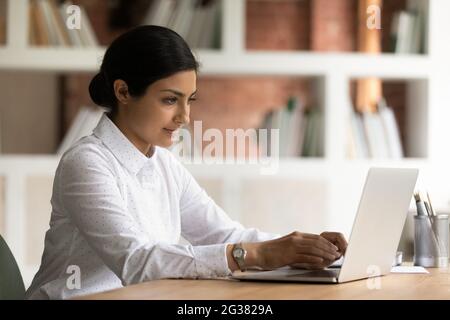 Focalizzato giovane donna di affari di etnia indiana che lavora sul computer. Foto Stock