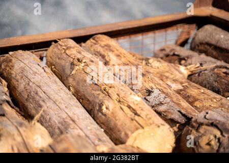 Tronchi di legno non trattati giacciono l'uno sopra l'altro in un contenitore di metallo all'esterno Foto Stock