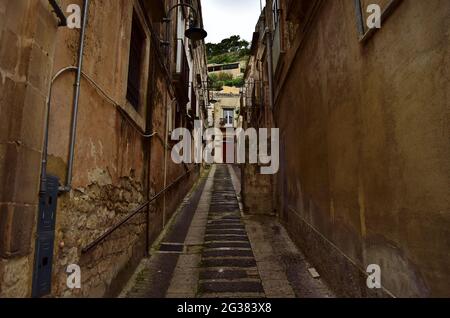 MODICA, SICILIA, ITALIA - 22 novembre 2015: Una strada stretta e palazzi nella città di Modica, Sicilia. Con strade ripide su colline e vecchi edifici Foto Stock