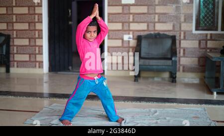 Yoga bambini. Piccolo ragazzo indiano facendo esercizio di yoga e guardando le istruzioni in TV. Concetto di giornata di yoga in tutto il mondo. Foto Stock