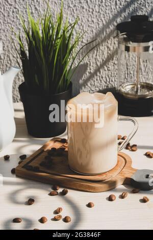 Caffè con panna e latte ghiacciato in tazza con manico sul tavolo. Foto Stock