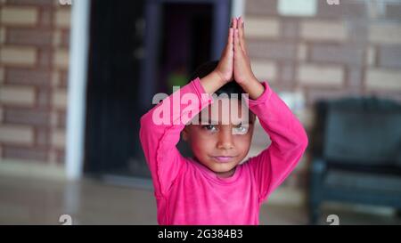 Indiano piccolo ragazzo carino che si esercita a casa. La famiglia lavora a casa. Concetto di giornata di yoga in tutto il mondo. Foto Stock