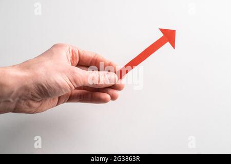 Tenendo con la mano una freccia rossa rivolta verso l'alto a destra Foto Stock