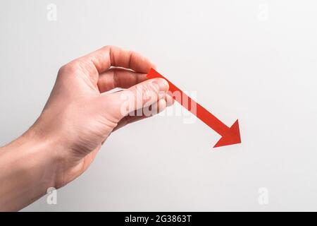Tenendo con la mano una freccia rossa rivolta verso il basso verso destra Foto Stock