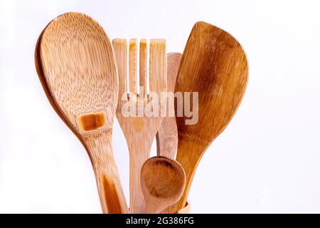 Utensili da cucina in legno usati come cucchiaio, spatola e forchetta su sfondo bianco. Foto Stock