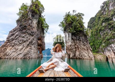 Viaggia Donna seduto in barca vicino a famose tre rocce nel Khao Sok Park, Thailandia Foto Stock