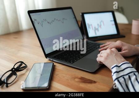 Donna che lavora con infografiche su smartphone, tablet e notebook. Foto Stock