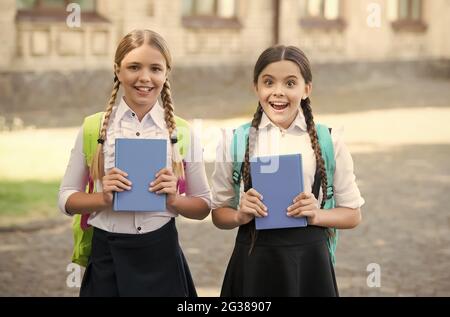 grande sorpresa per loro. Ragazze felici in uniforme di scuola. Gli allievi teen sorpresi con lo zaino tengono il copybook. Istruzione nella scuola primaria. Studentesse Foto Stock