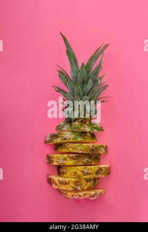 Ananas a fette su sfondo estivo di colore rosa. Anelli di ananas a fette di frutta tropicale. Composizione creativa piatta Foto Stock