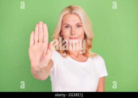 Foto sfocata ritratto anziano donna grave mostrando stop segno avvertenza vietato isolato colore verde pastello sfondo Foto Stock