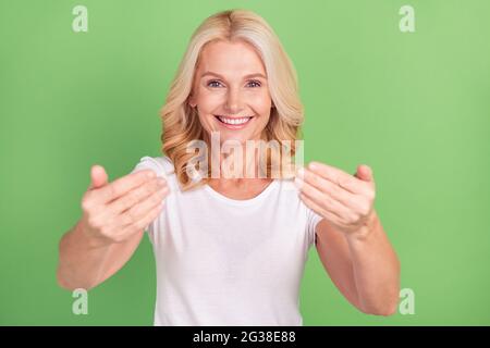 Foto ritratto anziano donna sorridente mostrando come sul segno felice isolato pastello verde sfondo colore Foto Stock