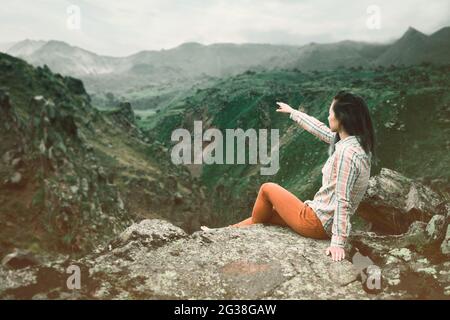 Donna turistica in montagna punta con la mano in lontananza. Foto Stock