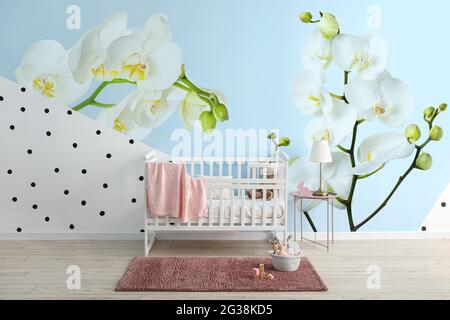 Interni eleganti della camera per bambini con splendidi fiori di orchidee sulla parete Foto Stock