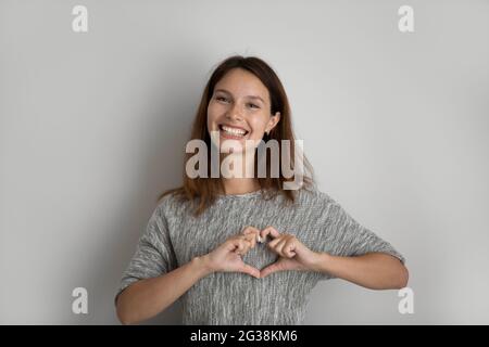 Ritratto della testa di una donna sorridente e attraente che mostra un gesto del cuore Foto Stock