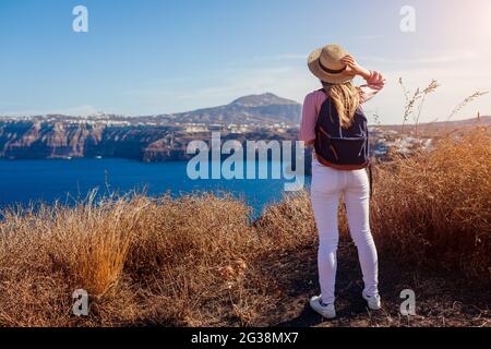 Donna viaggiatore a piedi sull'isola di Santorini, Grecia godendo del paesaggio. Happy escursionista con zaino gode di vista mare Caldera. Turismo Foto Stock