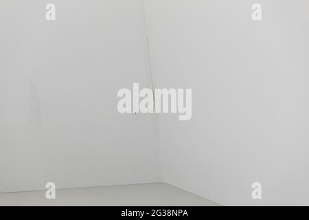 una piccola perdita d'acqua dal tetto su un soffitto bianco interno Foto Stock