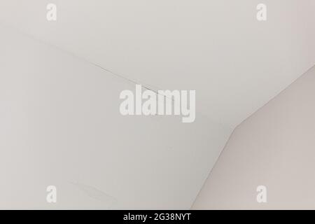 una piccola perdita d'acqua dal tetto su un soffitto bianco interno Foto Stock
