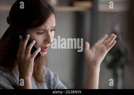 Primo piano donna infelice che parla al telefono, avendo una conversazione spiacevole Foto Stock