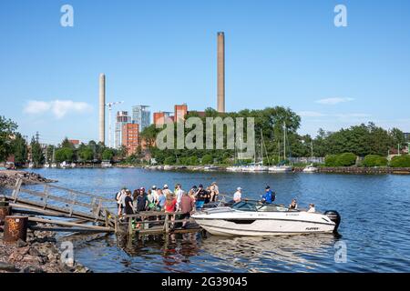 La gente gode il sole di venerdì sera su un molo nel distretto di Merihaka di Helsinki, Finlandia Foto Stock