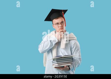 Studente di laurea maschile con libri su sfondo a colori Foto Stock