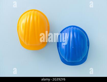 Gli hardhats in plastica appesi alla parete colorata Foto Stock